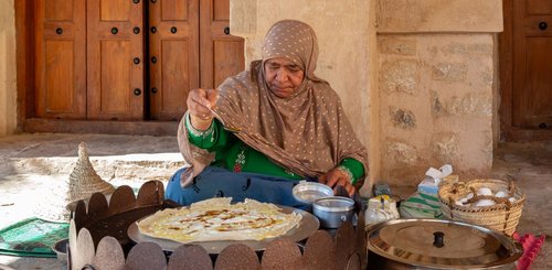 Frau im Oman bei der traditionellen Herstellung von Crepes in Nizwa